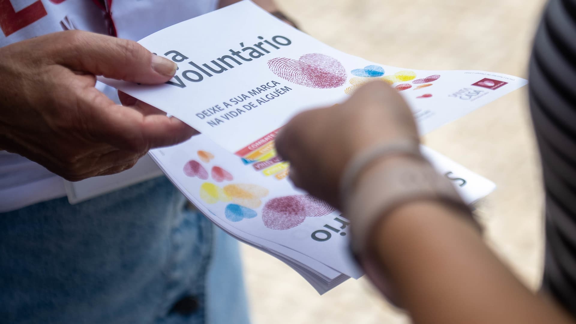 Pessoa distribui panfleto sobre voluntariado da Santa Casa