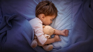 Criança a dormir com um urso de peluche