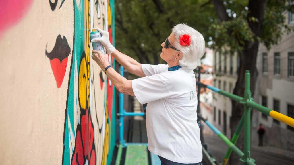 senhora idosa a pintar grafiti na Rua da Glória