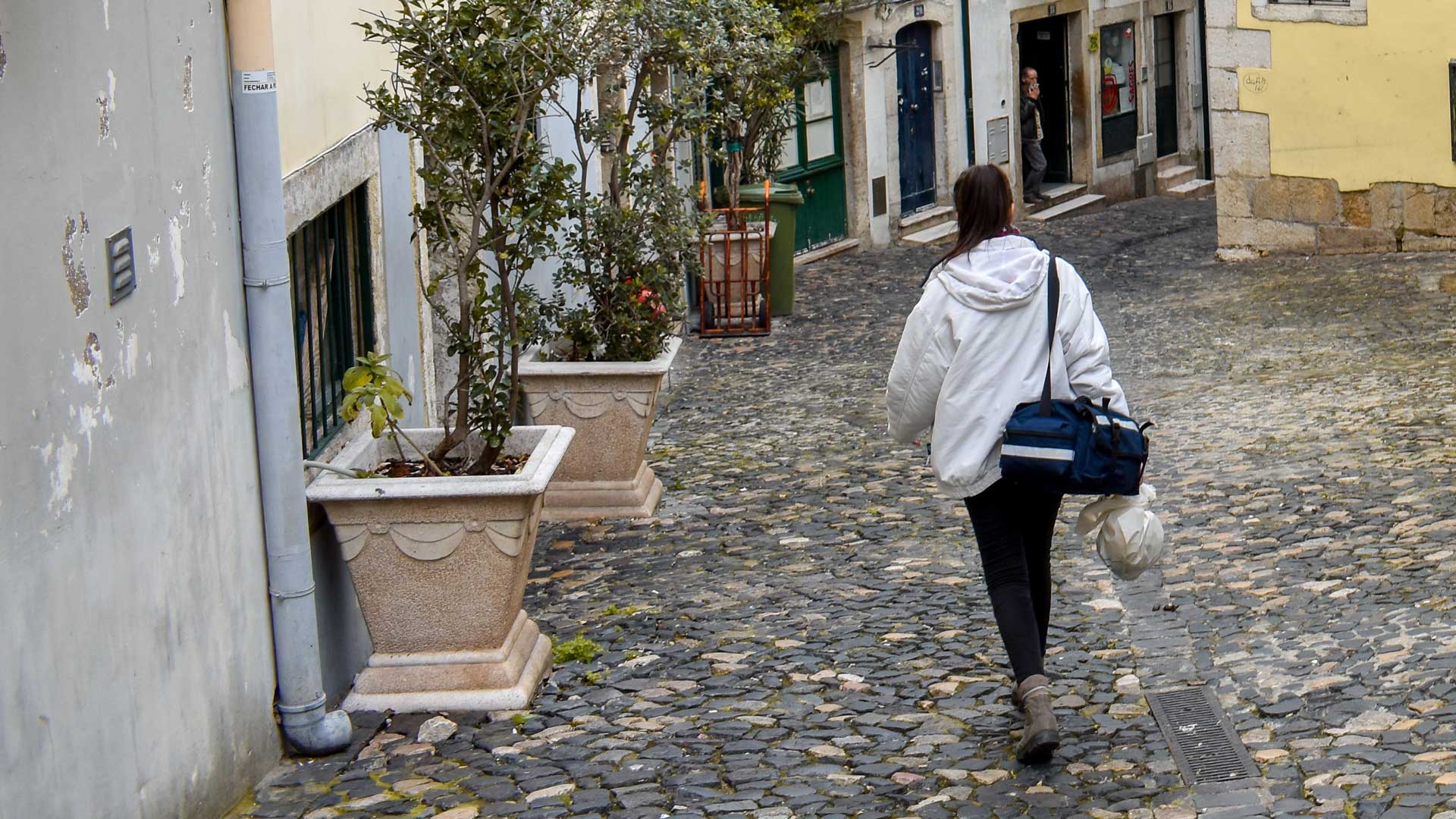 Médica caminha na rua para ir prestar Cuidados de Saúde no Domicílio