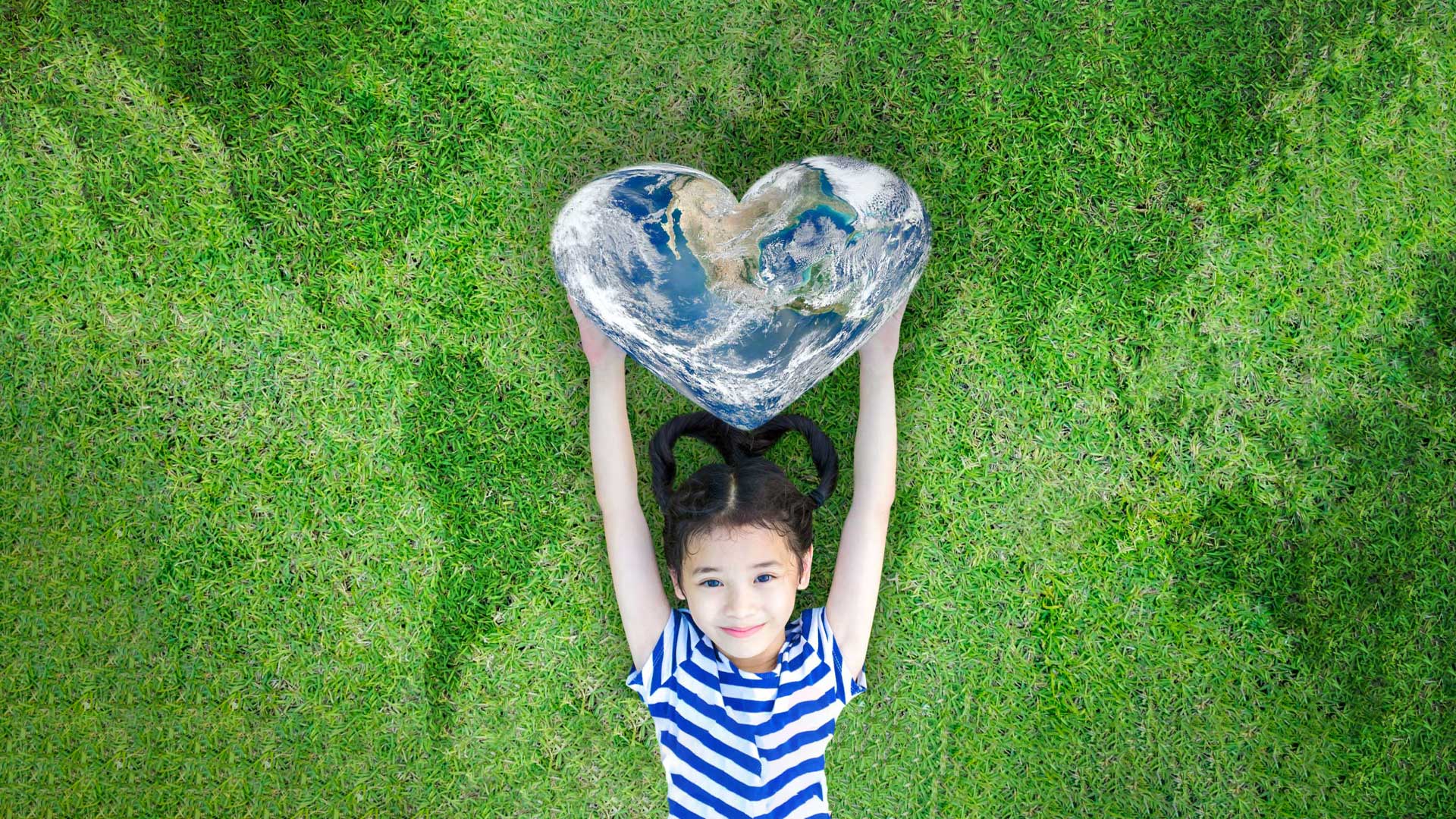 criança segura coração deitada na relva