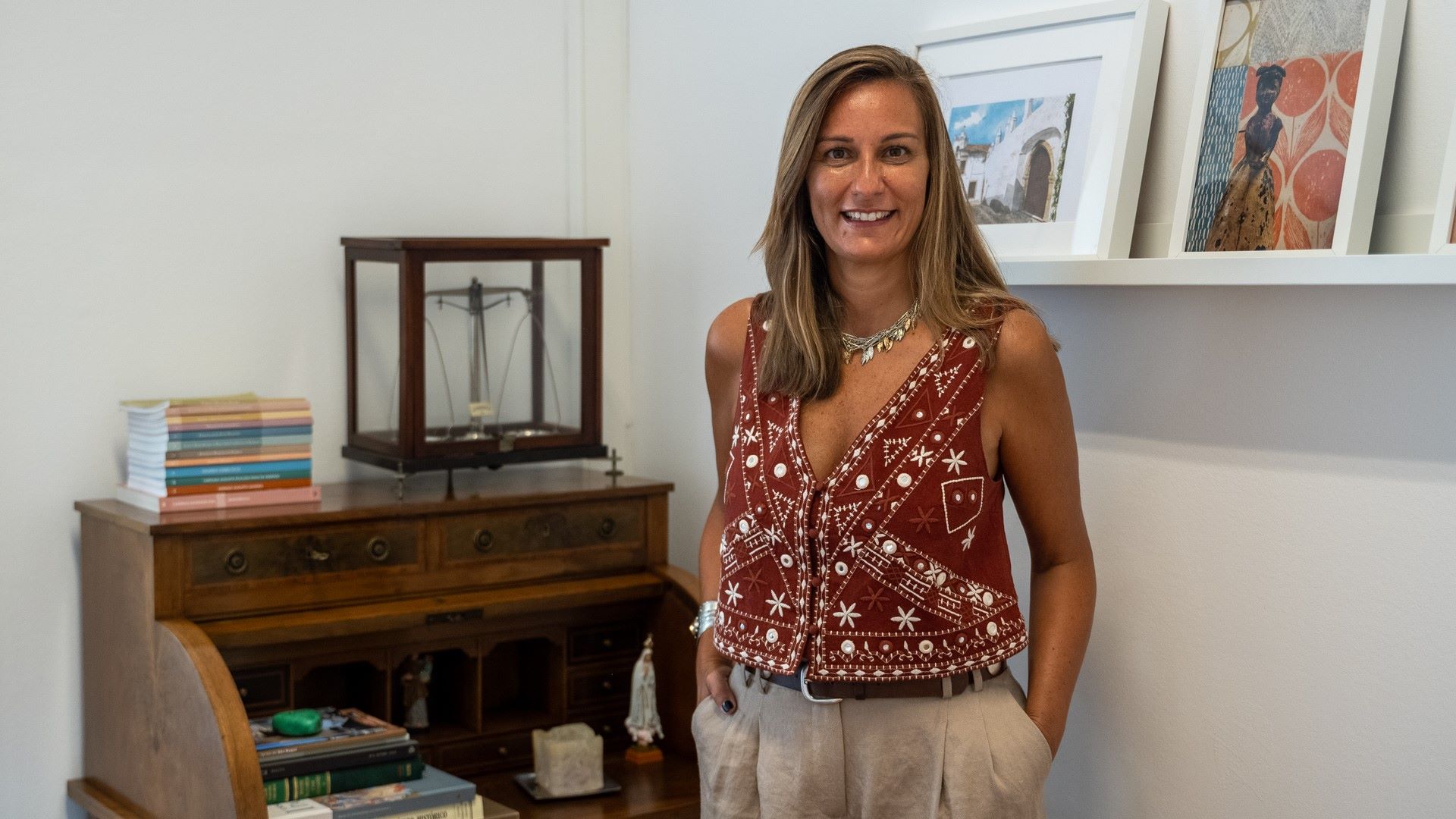 senhora posa com móvel por trás e prateleira de livros