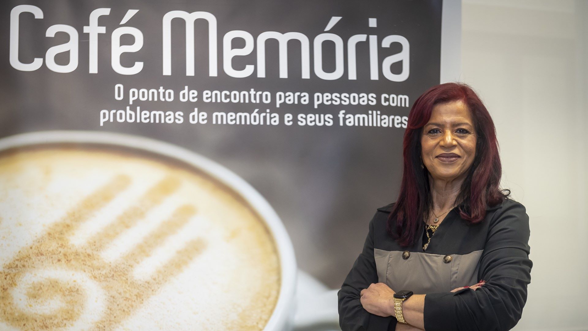 coordenadora do café memória com cartaz atrás
