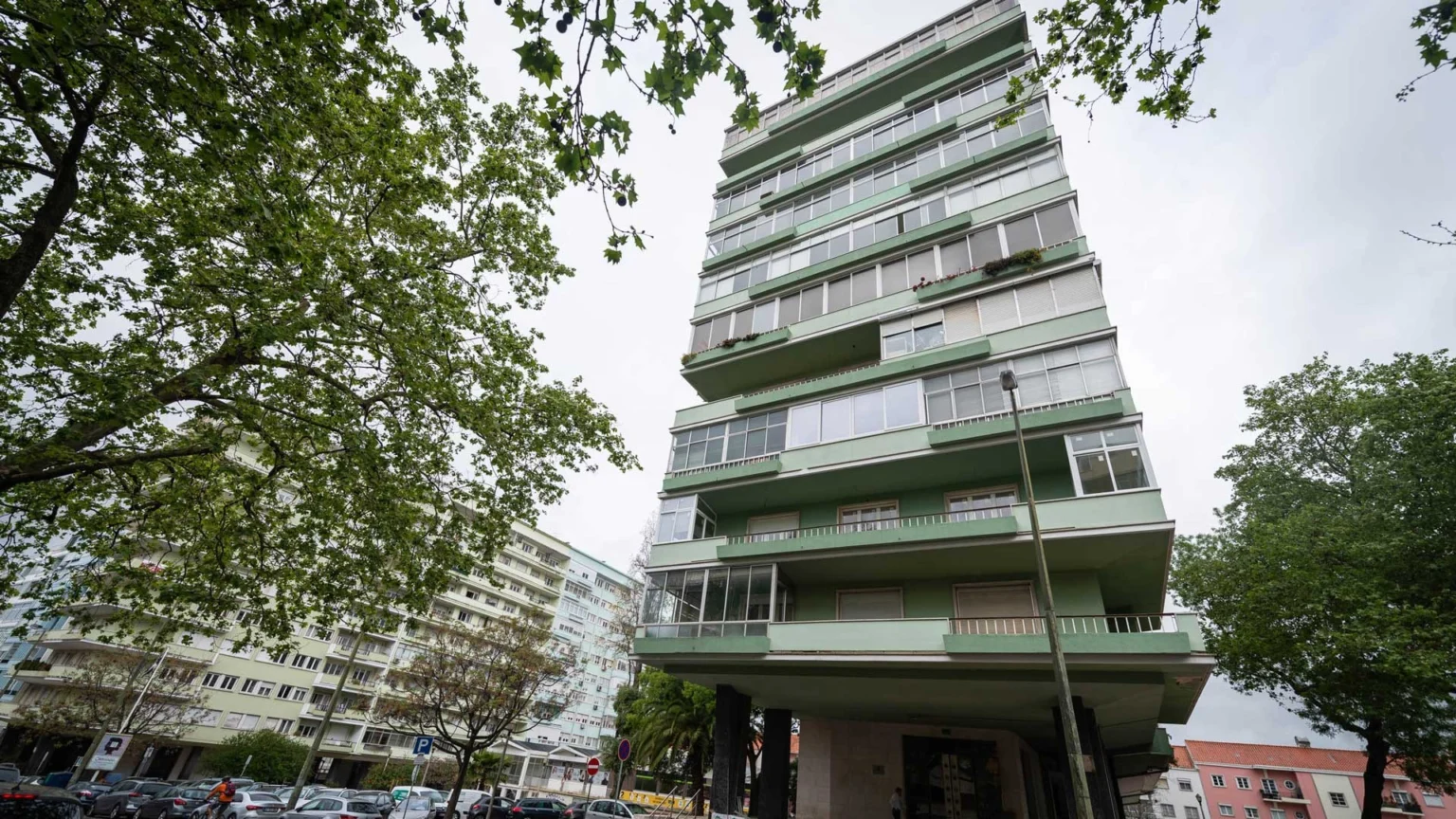 Fachada do prédio alto de varandas verdes da Av. Estados Unidos da América, 116, entre árvores