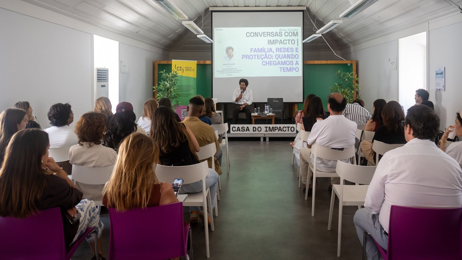 pessoas em plateia na casa do impacto assistem a conversa sobre acolhimento familiar