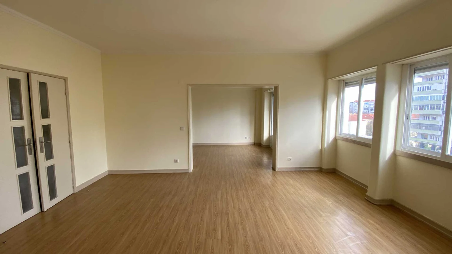 Sala ampla com chão de madeira clara, duas janelas e porta envidraçada dupla, na Av. Estados Unidos da América, 116