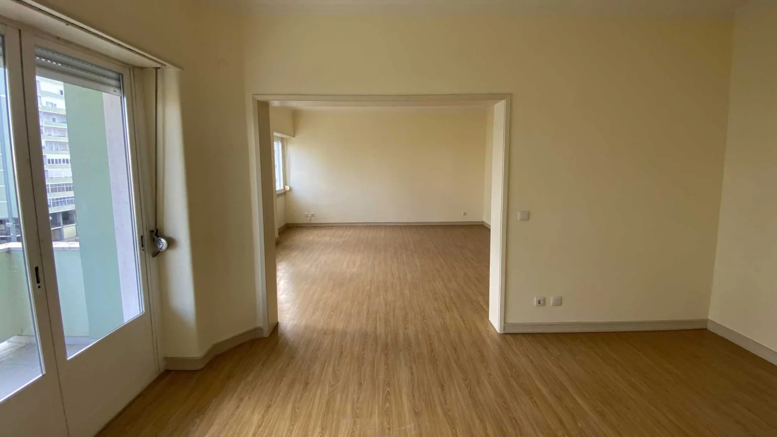 Sala com porta-janela para a varanda à esquerda e vão aberto para a outra sala, na Av. Estados Unidos da América, 116