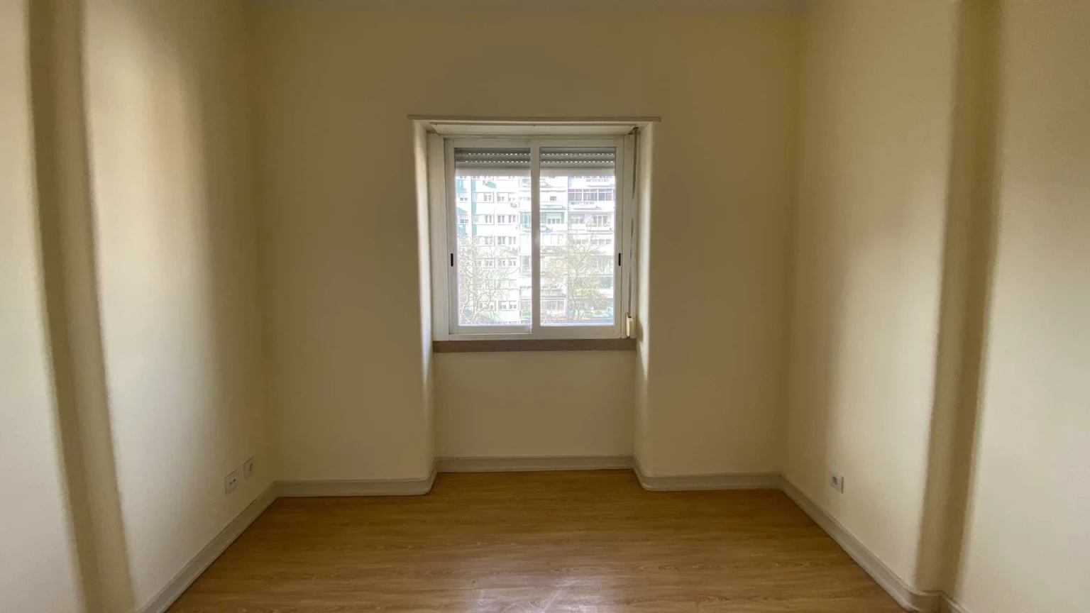 Quarto pequeno com chão de madeira e janela de guilhotina ao centro, na Av. Estados Unidos da América, 116