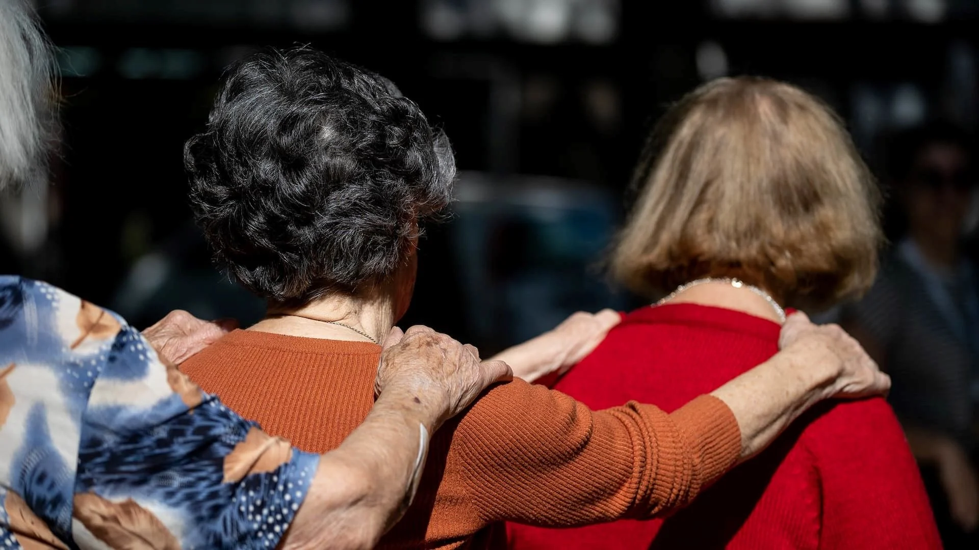 idosos-em-fila 3 mulheres idosas em filha colocando as mãos nos ombros da senhora à sua frente