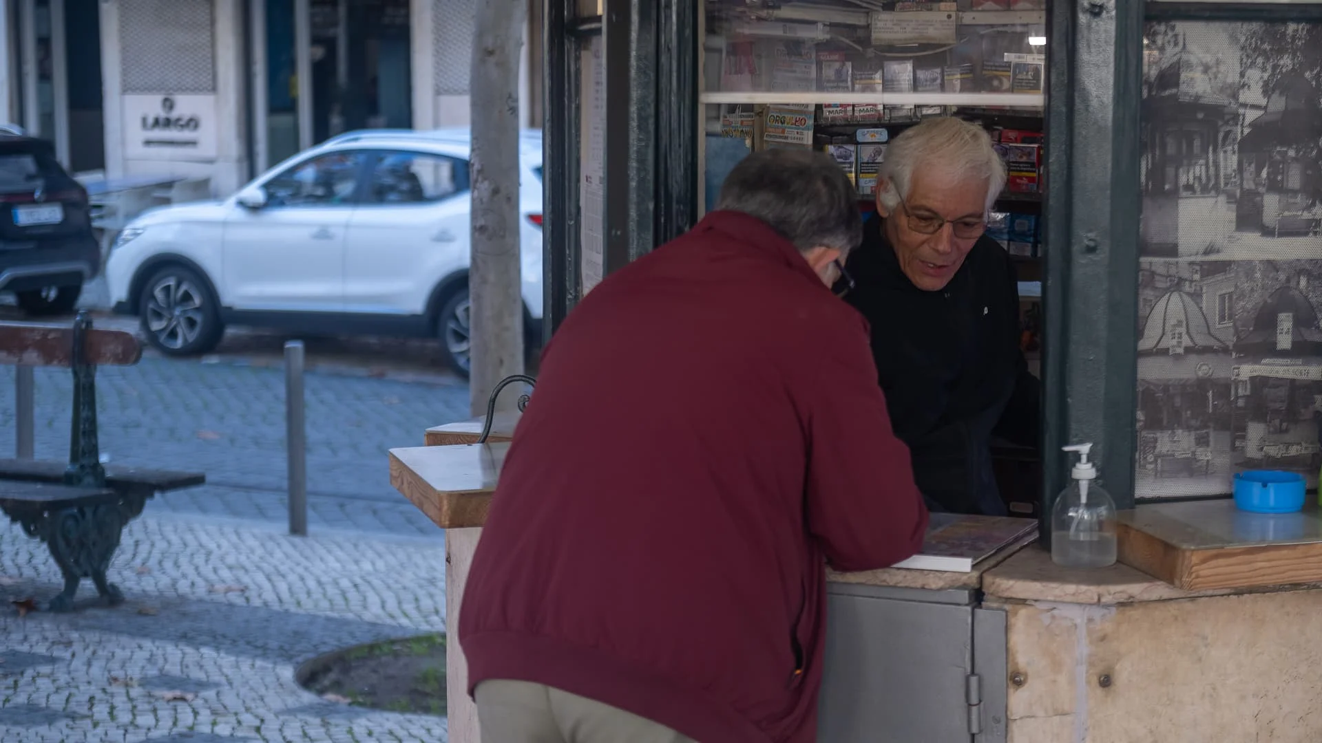 Senhor dentro de quiosque a falar com outro senhor