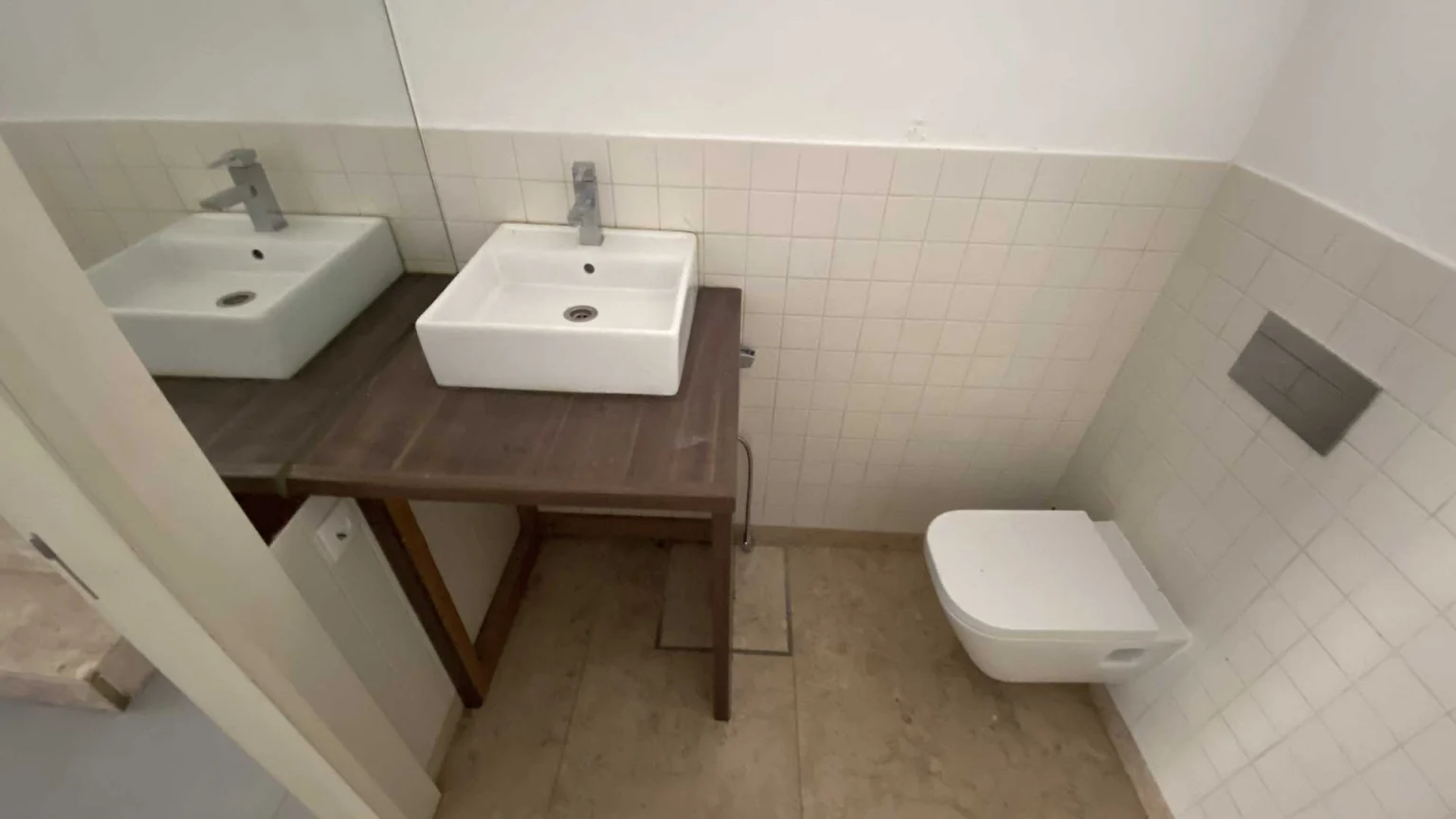 Shop bathroom with two washbasins on a wooden counter and a wall-hung toilet