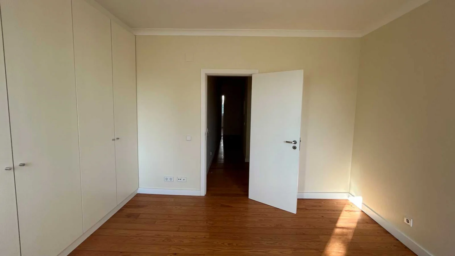 Quarto com roupeiros brancos à esquerda e porta aberta para o corredor, na Rua Silva Carvalho, 26