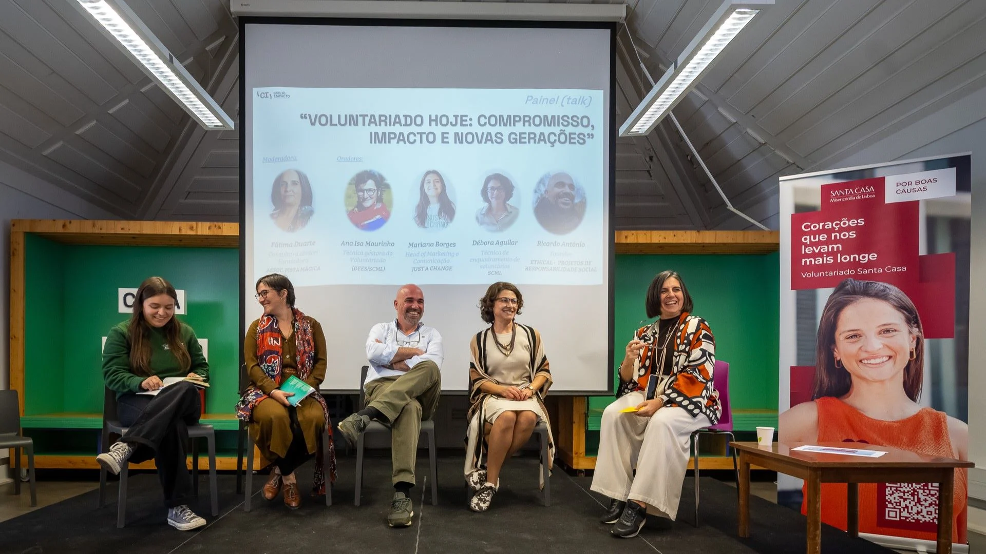 cinco pessoas (quatro homens e uma mulher), sentados e e a rirem, falam sobre o voluntariado.